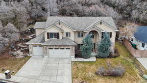 Traditional-style home with concrete driveway, stone siding, fence, a front lawn, and stucco siding