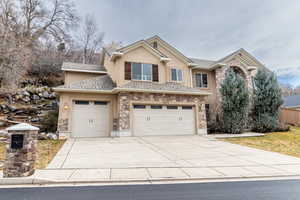 View of front of house featuring stone siding, concrete driveway, and stucco siding