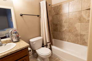 Bathroom with toilet, tile patterned flooring, shower / tub combo with curtain, and vanity