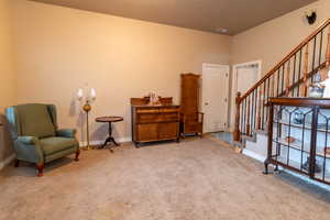 Living area featuring stairs, carpet flooring, and baseboards