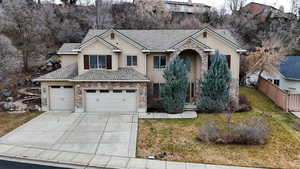 View of front of house featuring stone siding, a front lawn, fence, and stucco siding