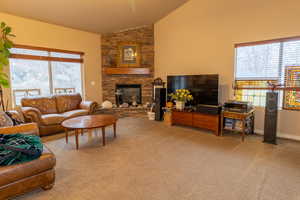 Living area with a wealth of natural light, light carpet, and a stone fireplace