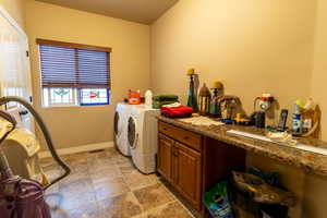 Washroom featuring cabinet space, visible vents, baseboards, stone finish floor, and independent washer and dryer