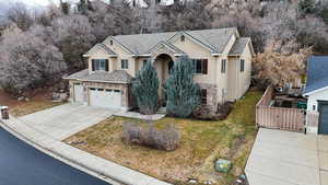 View of front of home featuring stucco siding, a front yard, a garage, stone siding, and driveway