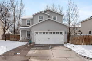 Traditional home with a garage, fence, concrete driveway, and stucco