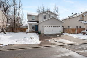 Traditional-style house with fence, driveway, an attached garage, and stucco