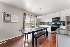 Kitchen with black microwave, range with electric stovetop, white cabinetry and decorative backsplash