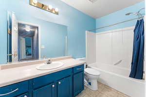 Bathroom featuring shower / tub combo with curtain, vanity, and toilet