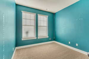 Carpeted empty room with visible vents and baseboards