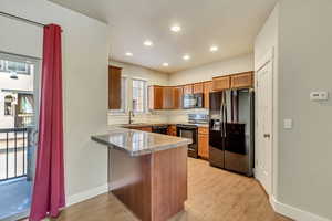 Kitchen featuring light wood-type flooring, a sink, a peninsula, and black appliances