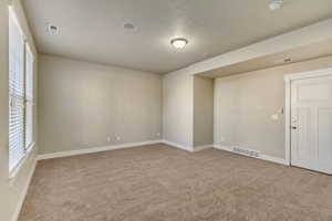 Spare room with carpet, visible vents, and baseboards