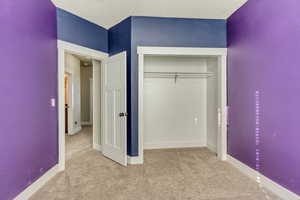 Unfurnished bedroom with carpet floors, baseboards, and a closet