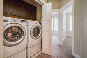 Laundry room with cabinet space, independent washer and dryer, and light colored carpet