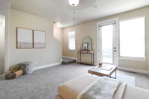 Living room with light carpet, healthy amount of natural light, and ceiling fan