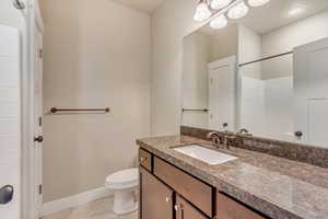 Bathroom featuring a shower, toilet, vanity, baseboards, and tile patterned floors