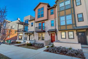 View of property featuring stucco siding, a balcony, a residential view, and a pergola