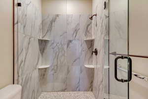 Bathroom featuring a marble finish shower and toilet