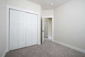 Unfurnished bedroom featuring carpet flooring and a closet