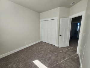 Unfurnished bedroom featuring carpet flooring, visible vents, and baseboards