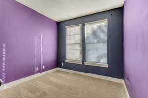 Spare room featuring carpet floors, visible vents, and baseboards