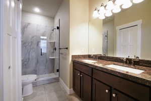 Full bathroom with a marble finish shower and double vanity