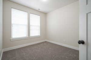 Empty room with dark colored carpet and baseboards