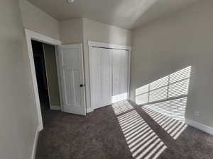 Unfurnished bedroom featuring carpet flooring, baseboards, and a closet