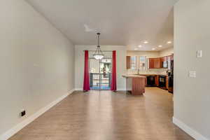 Kitchen with black dishwasher, light wood-style flooring, stainless steel microwave, a peninsula, and light countertops