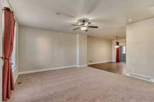 Carpeted spare room with baseboards, visible vents, and a ceiling fan