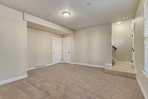 Carpeted spare room featuring visible vents, stairway, and baseboards