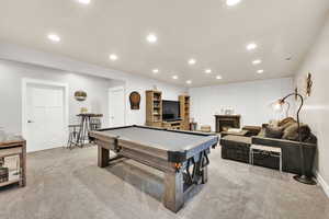 Recreation room with a warm lit fireplace, recessed lighting, light colored carpet, and pool table