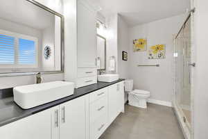 Full bath featuring toilet, a sink, and a marble finish shower