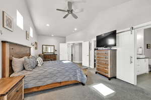 Bedroom featuring a barn door, ceiling fan, carpet, high vaulted ceiling, and recessed lighting