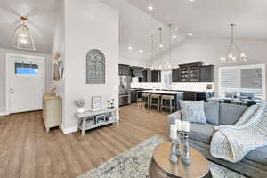 Living area featuring a chandelier, light wood-style floors, and high vaulted ceiling