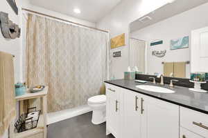 Bathroom with a shower with shower curtain, visible vents, vanity, and toilet