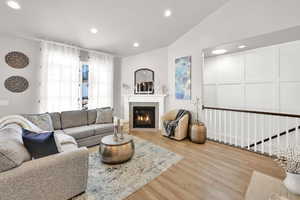 Living room featuring a glass covered fireplace, wood finished floors, and recessed lighting