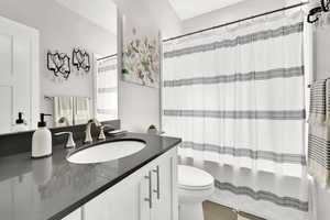 Bathroom with shower / bath combination with curtain, vanity, and toilet