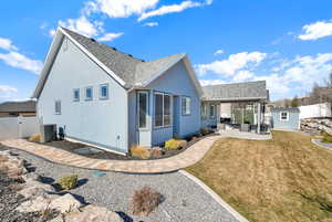 Back of house with a gate, an outdoor structure, central air condition unit, a patio area, and stucco siding