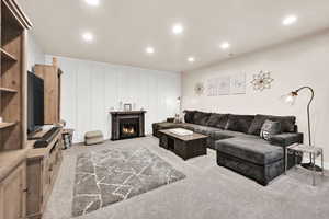 Living room featuring light carpet, a lit fireplace, visible vents, and recessed lighting