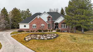 Traditional-style home featuring driveway, stucco siding, a front lawn, and brick siding