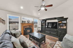 Living area featuring lofted ceiling, a tile fireplace, recessed lighting, wood finished floors, and a ceiling fan