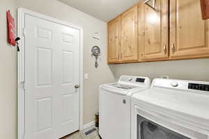 Laundry room with baseboards, light tile patterned floors, cabinet space, and washer and dryer