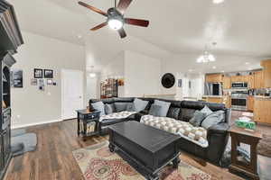 Living room with recessed lighting, baseboards, dark wood-type flooring, and ceiling fan with notable chandelier