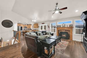 Living area with a fireplace, dark wood finished floors, lofted ceiling, recessed lighting, and baseboards