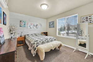 Bedroom featuring carpet floors, wood walls, a textured ceiling, and baseboards