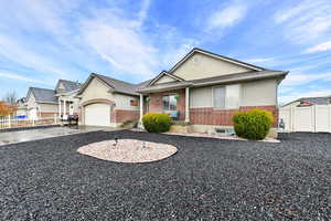 Single story home with a garage, driveway, brick siding, and fence