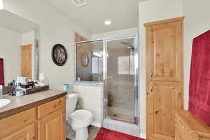 Full bathroom featuring toilet, a stall shower, visible vents, and vanity