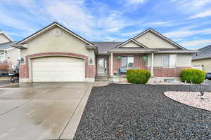 Ranch-style house with a garage, brick siding, a shingled roof, driveway, and stucco siding