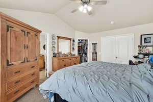 Carpeted bedroom with lofted ceiling, ceiling fan, and ensuite bath