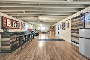 Interior space with freestanding refrigerator, wood finished floors, and a barn door